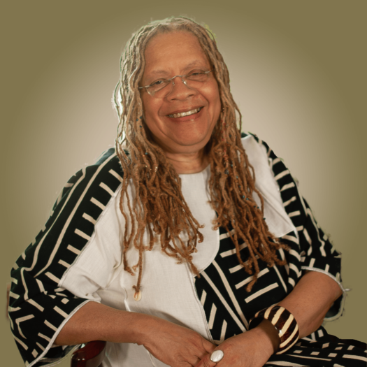 Gretta Chamberlain Profile Image - sitting in chair in a black and white outfit.